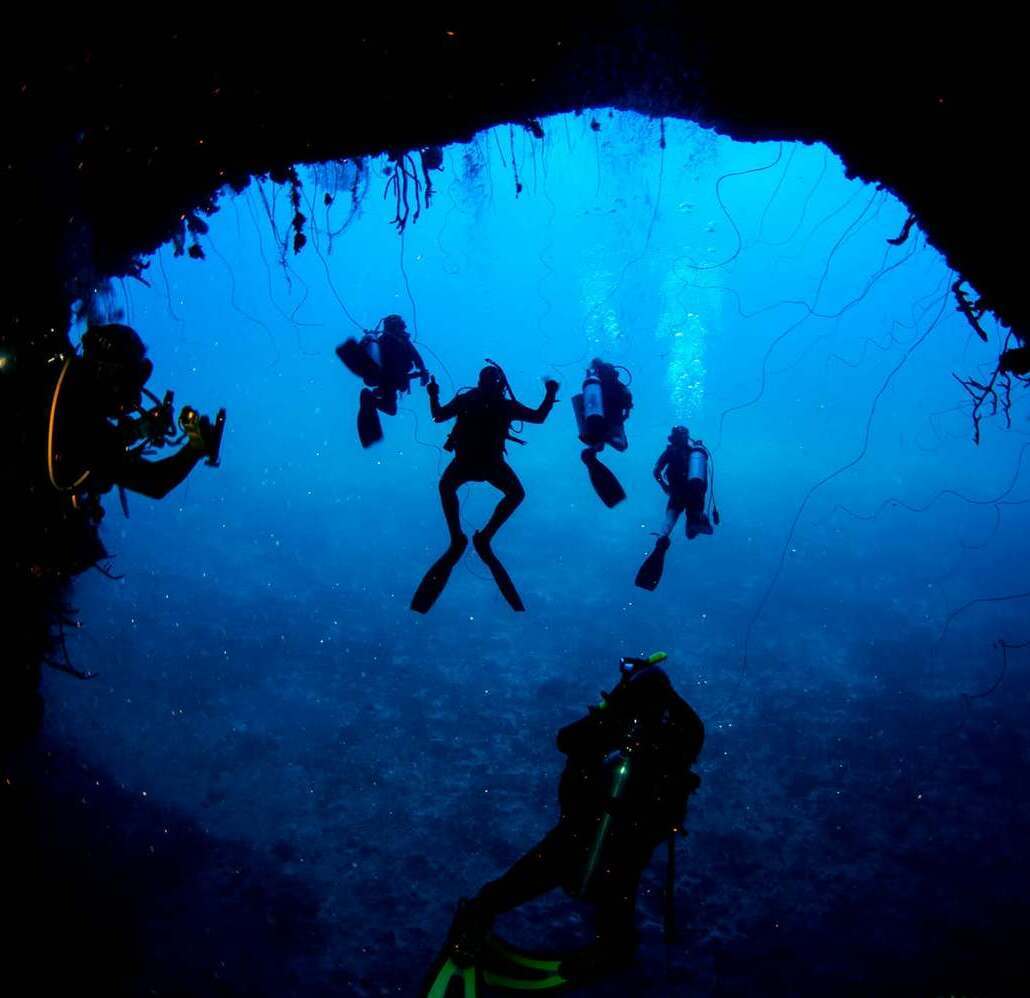 Cabo Cabrón cavern dive Group of scuba divers silhouetted inside a cavern at Cabo Cabrón National Park
